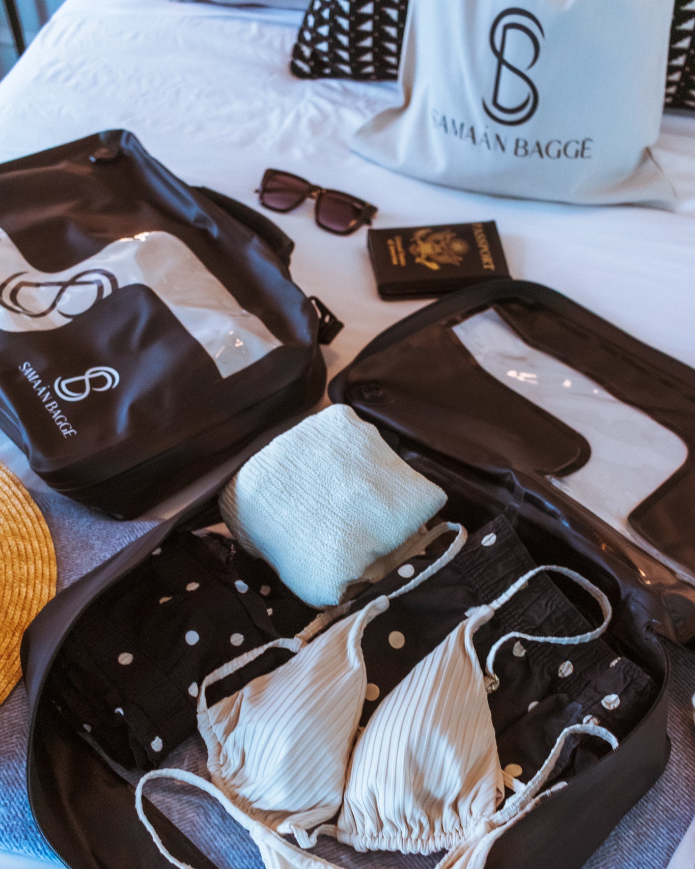 Set of women's bikini in a 'Samaan Bagge' branded black travel compression packing cube with  travel accessories on top of a white bed